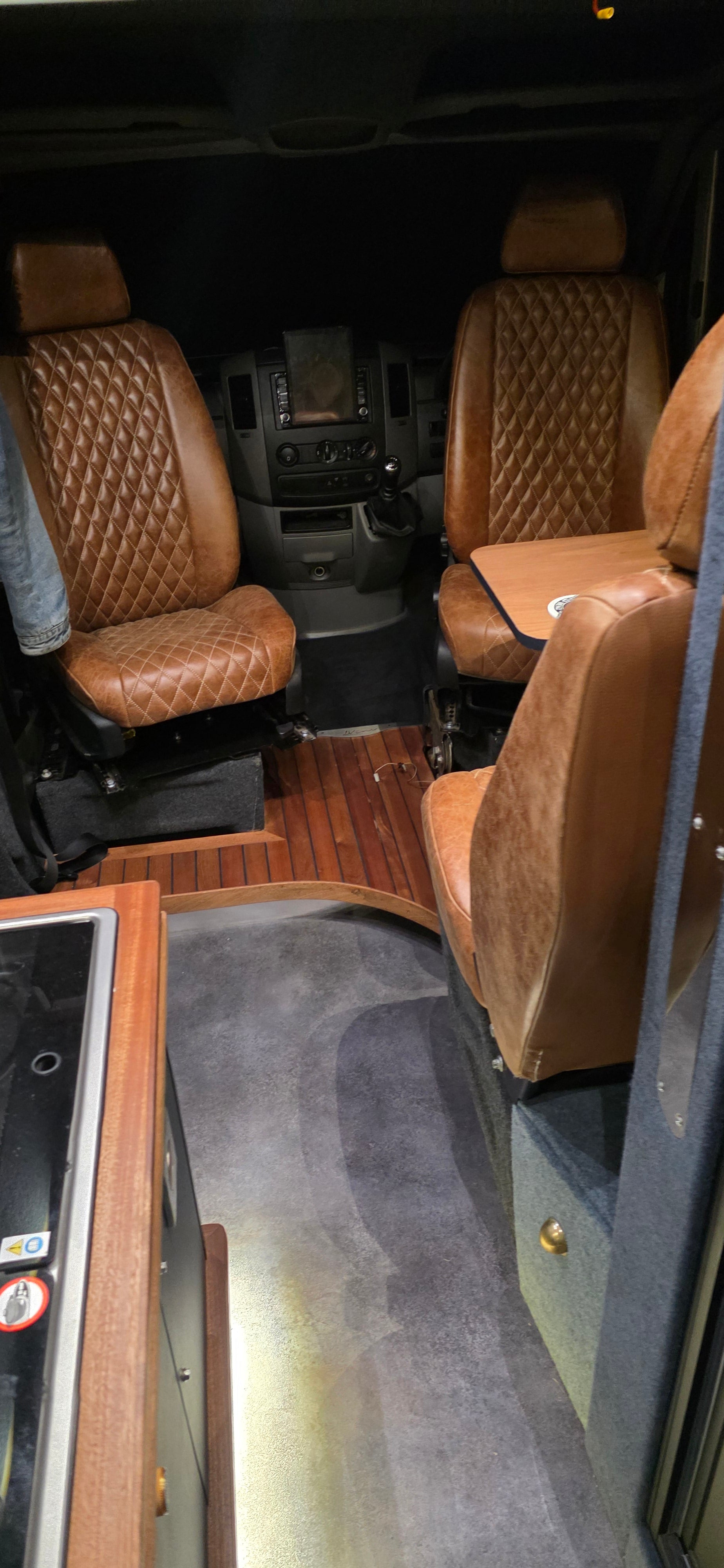 Camper interior with brown leather seats and dashboard.