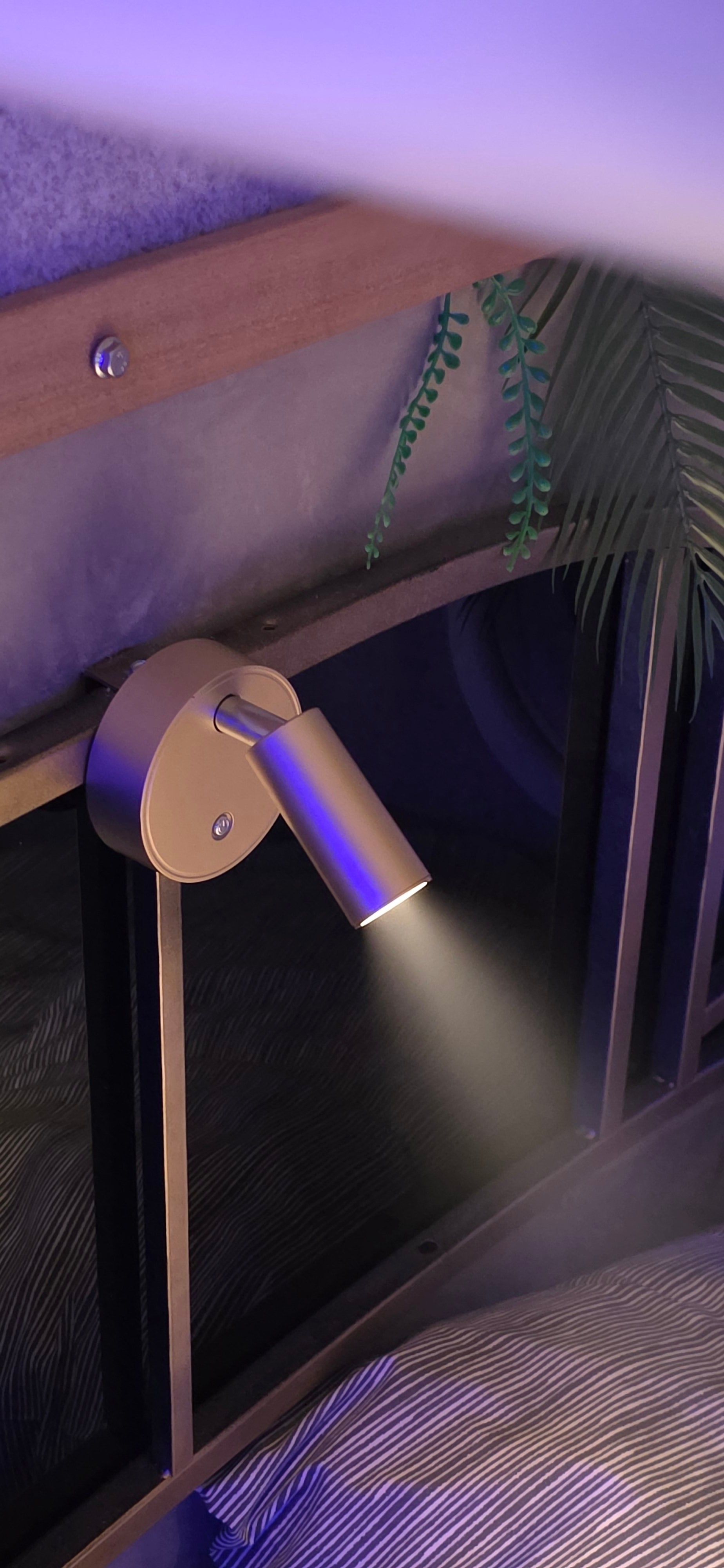Wall-mounted lamp with a purple light on a wooden surface. Boeing first class interior cabin