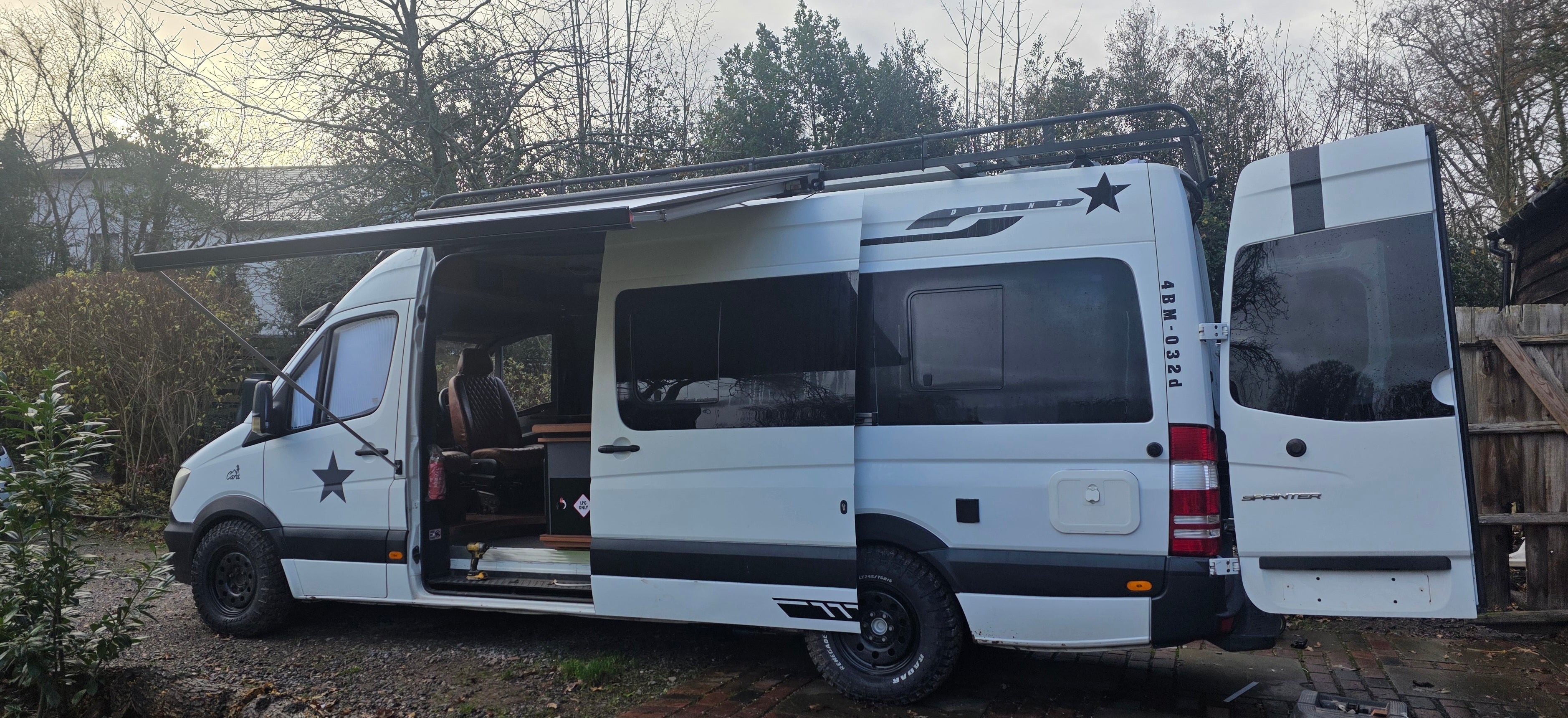 White van with open doors in a wooded area, campervan converted from a mercedes sprinter vw crafter camper can off grid